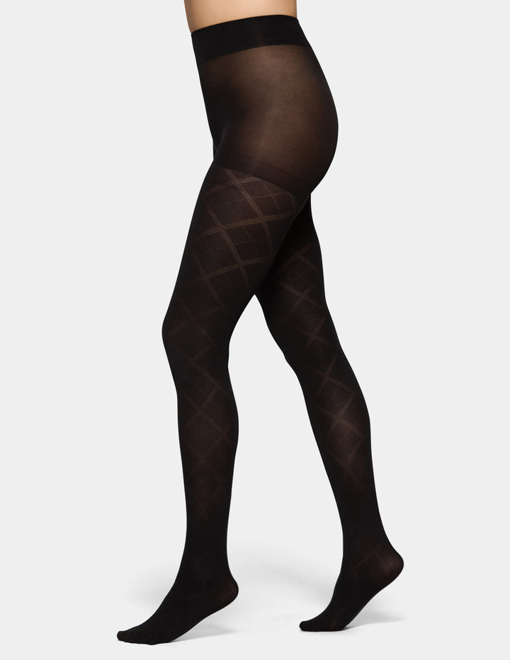 Black sheer hosiery with a subtle diamond pattern on the legs, shown on a model's lower body against a white background.