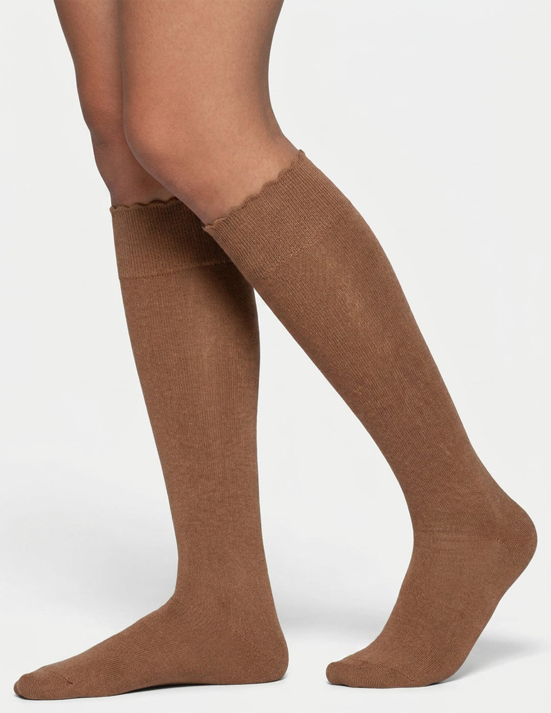 A pair of knee-high socks in a warm brown color, shown on a model's legs against a light gray background.
