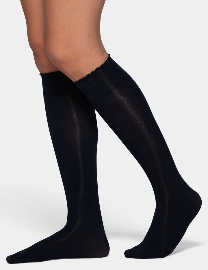 Dark navy knee-high compression socks worn on a model's legs, shown from the calf down against a light gray background.