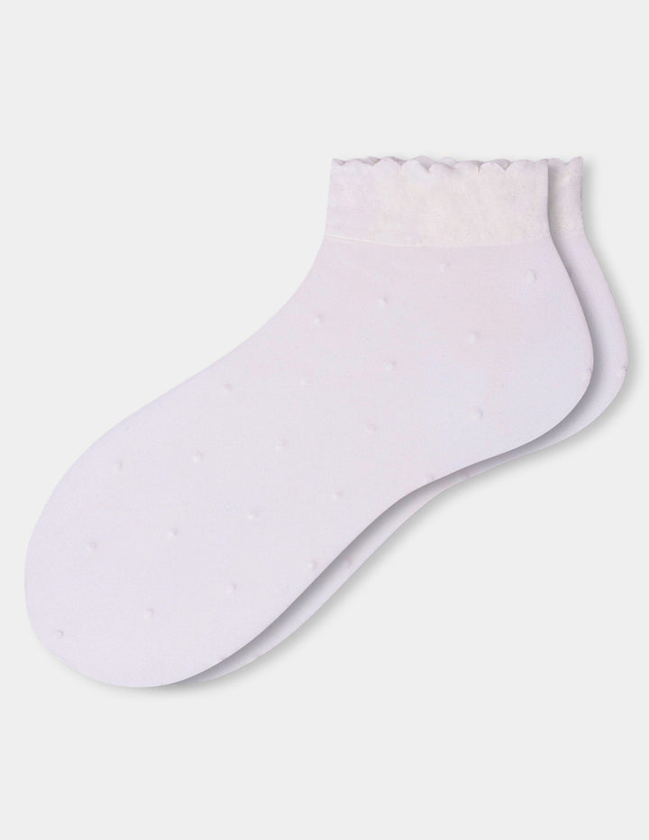 A pair of ivory ankle socks with a textured, dotted pattern and a ruffled trim at the top, displayed against a light gray background.