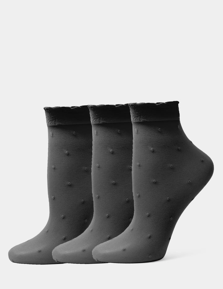 Three black ankle socks with a textured dotted pattern and ribbed cuffs, arranged in a row against a light gray background.