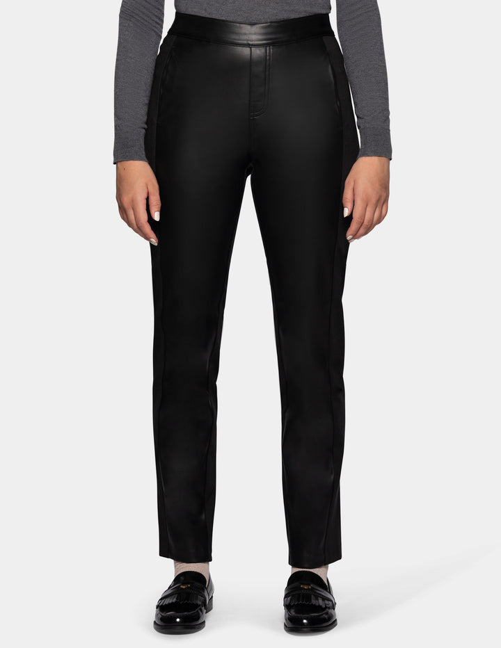 A model wearing black faux leather pants, a long sleeve grey top, and black loafers.