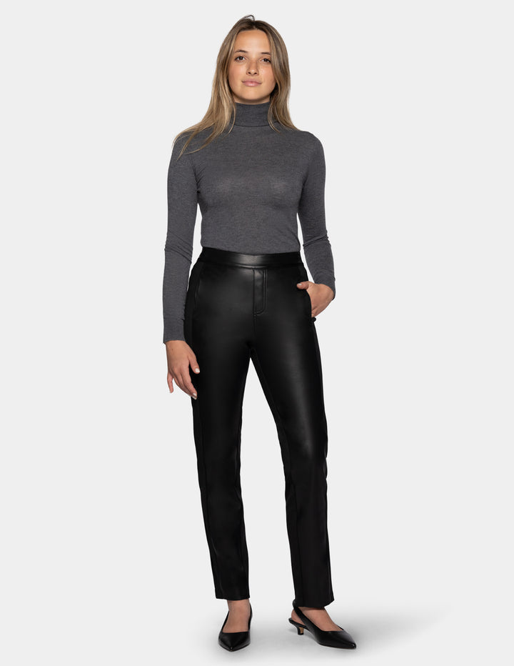 A model wearing black faux leather pants, a long sleeve grey top, and black kitten heels.
