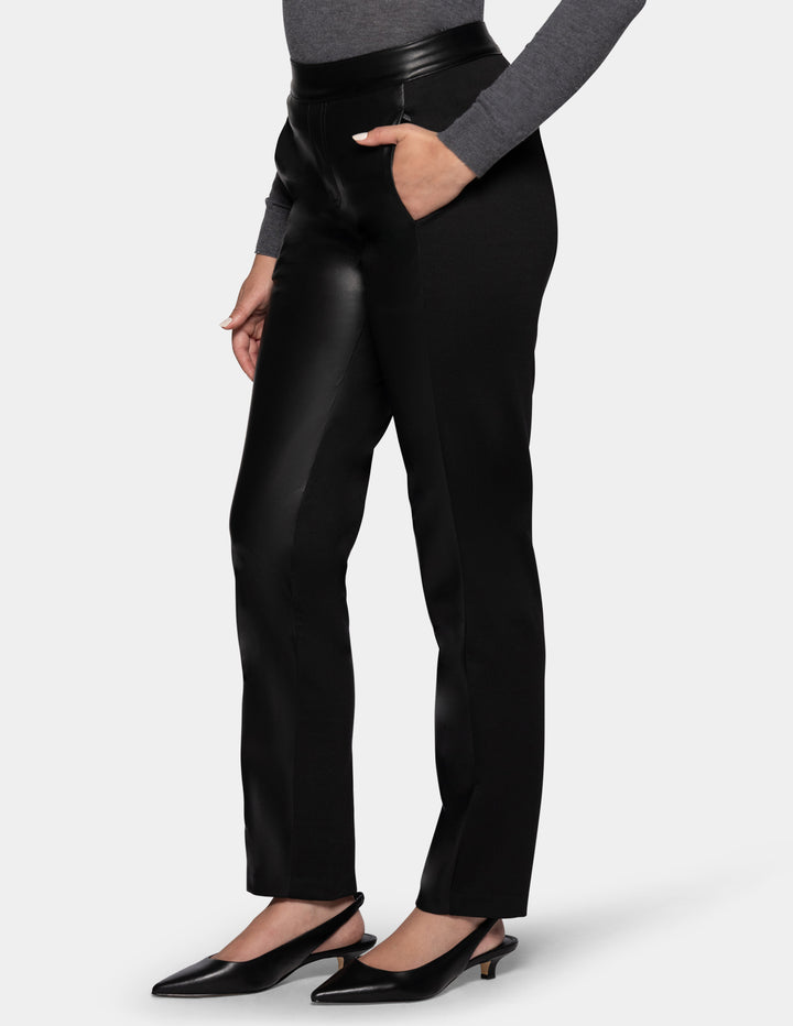 A model wearing black faux leather pants, a long sleeve grey top, and black kitten heels.