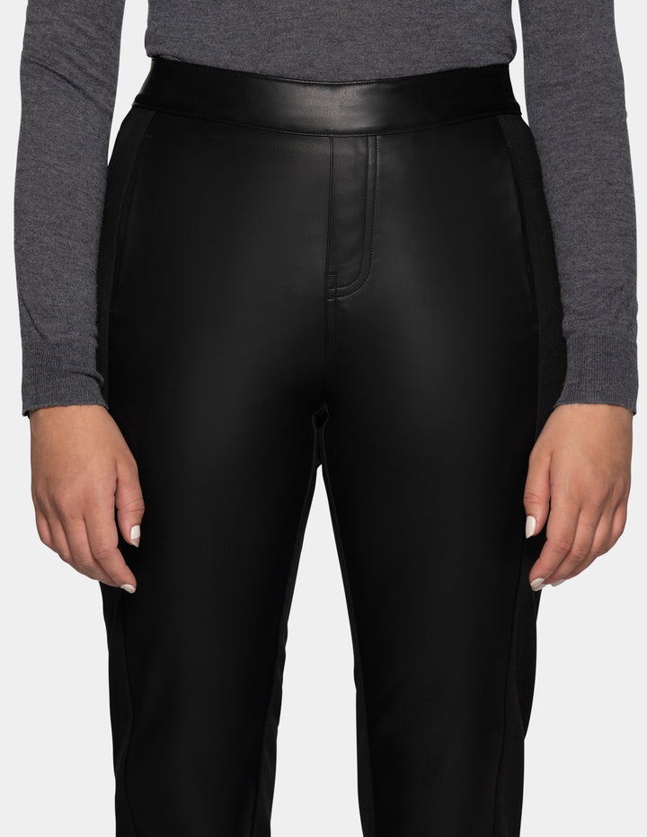 A model wearing black faux leather pants and a long sleeve grey top.