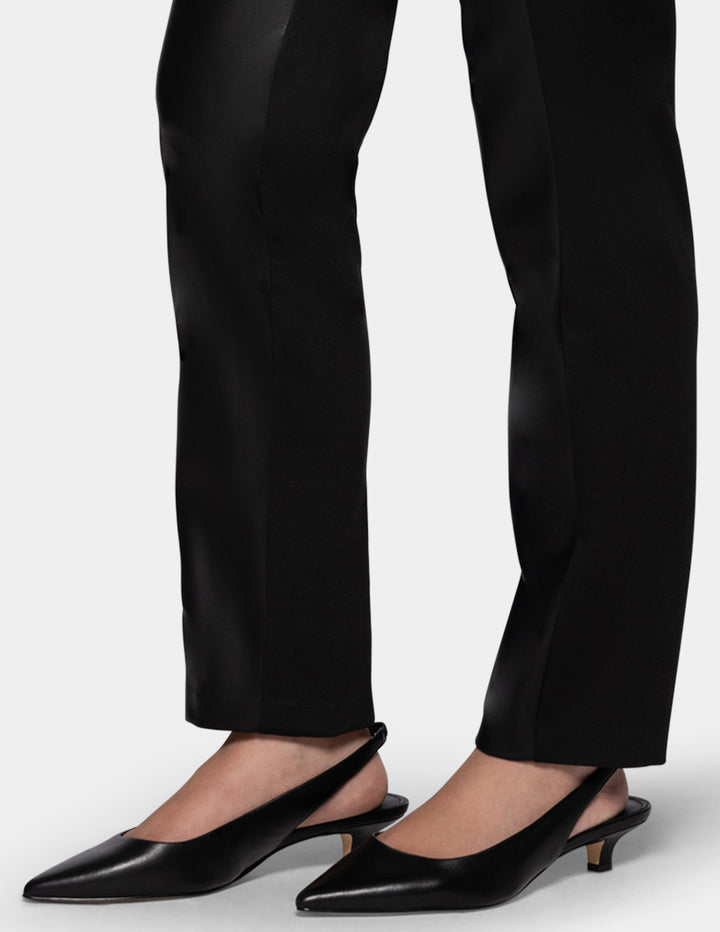 A model wearing black faux leather pants and black kitten heels.