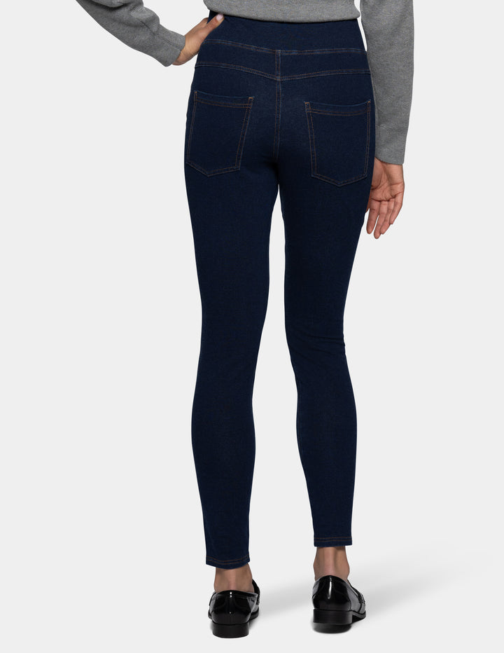 Rear view of a person wearing dark navy blue leggings with a gray long-sleeve top and black shoes, shown against a light gray background.