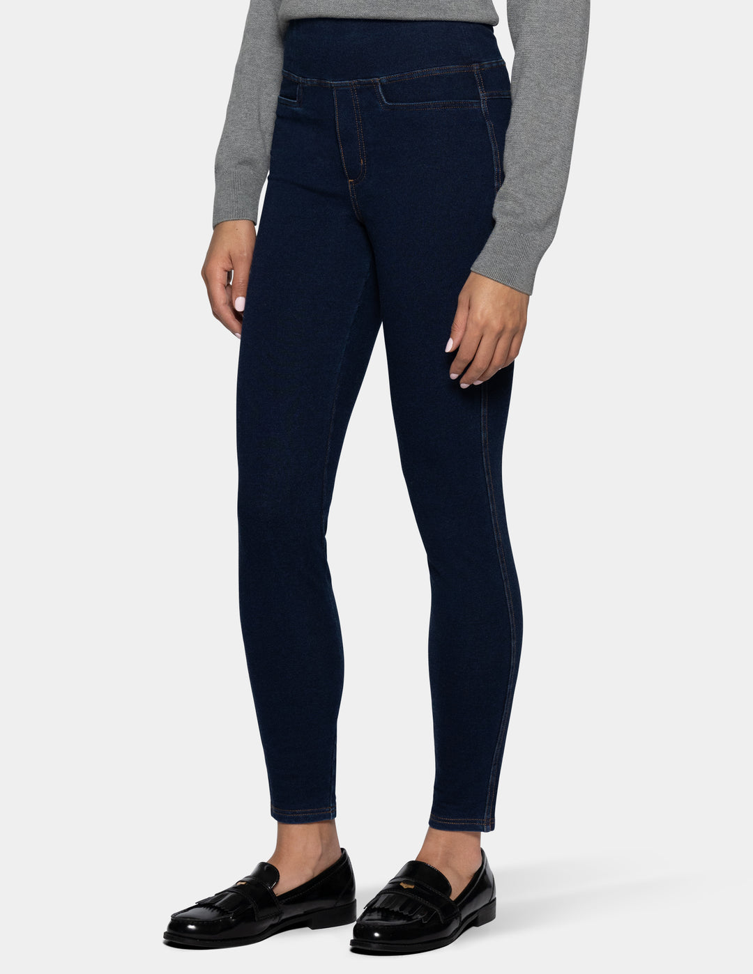 A model wearing dark navy blue leggings, a gray long-sleeve top, and black patent leather loafers, shown from the waist down against a light gray background.