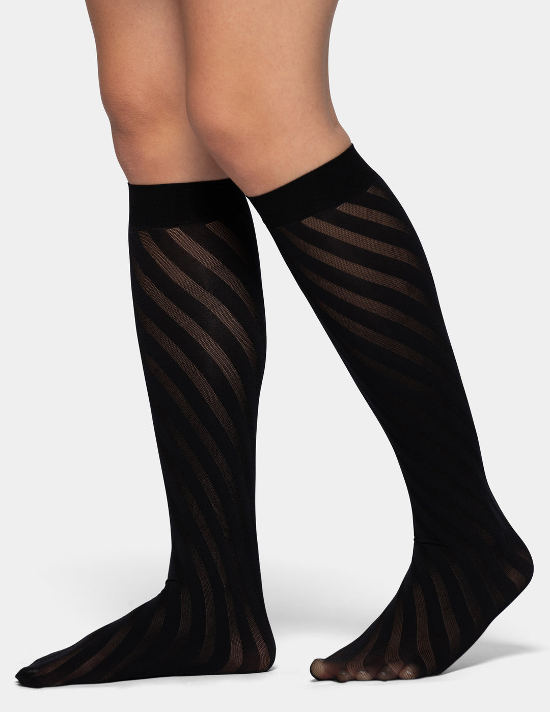 Black knee-high sheer striped tights worn on a model's legs, shown against a light gray studio background.