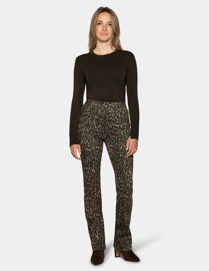 A model wearing olive leopard print leggings and a long sleeve dark color top, paired with dark brown suede boots against a light gray background.