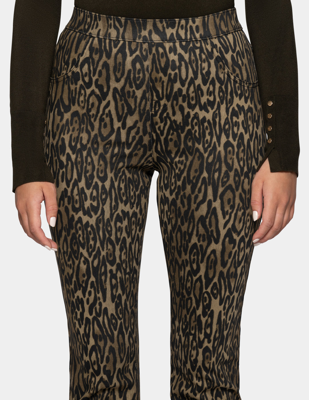 A close-up of a model wearing olive leopard print leggings and a long sleeve dark color top against a light gray background.