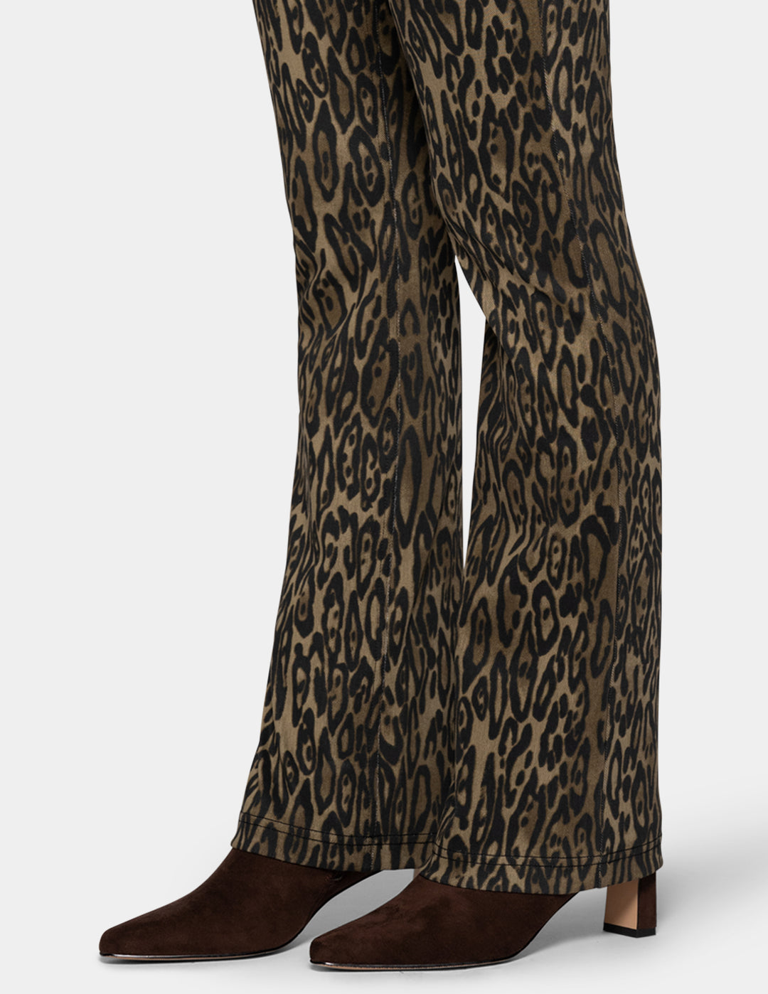 A close-up of a model wearing olive leopard print leggings paired with dark brown suede boots against a light gray background.