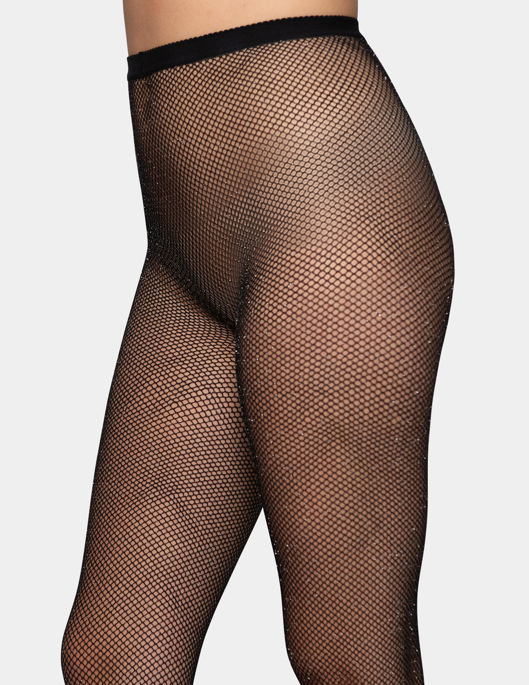 A detailed view of a model wearing black fishnet tights photographed against a light gray background.