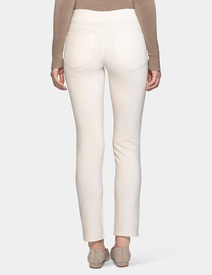 A backside view of a model wearing off white corduroy pants with a long sleeve beige top and matching color shoes