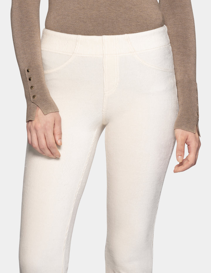 A close-up of a model wearing off white corduroy pants with a long sleeve beige top