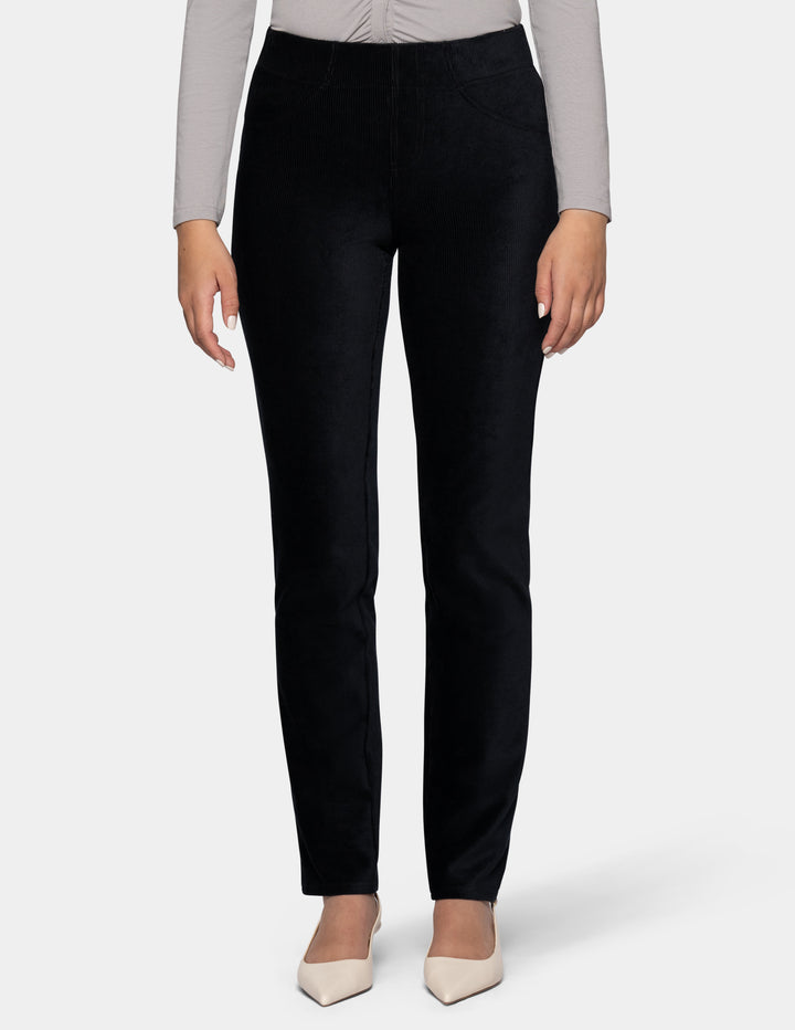 A model wearing black corduroy pants and a long sleeve grey top with ivory pointed toe shoes from the waist down