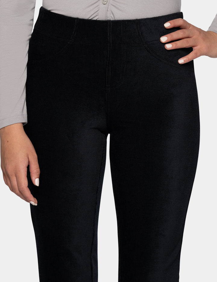A close-up view of a model wearing black corduroy pants and a long sleeve grey top