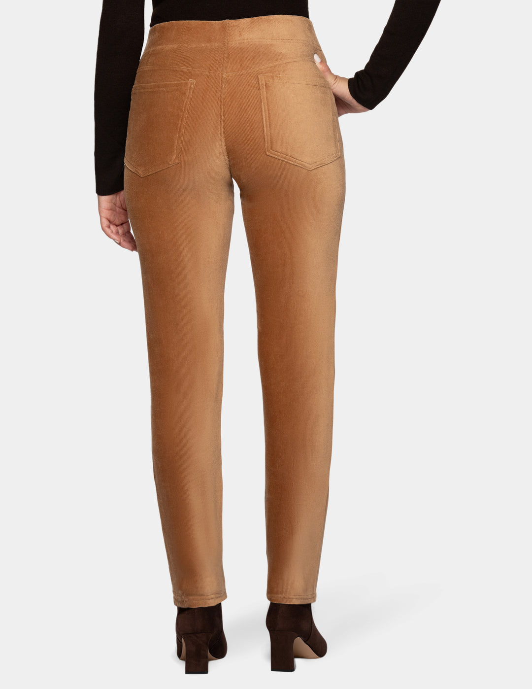 A backside view of a model wearing tan corduroy pants with a long sleeve black top and dark brown boots