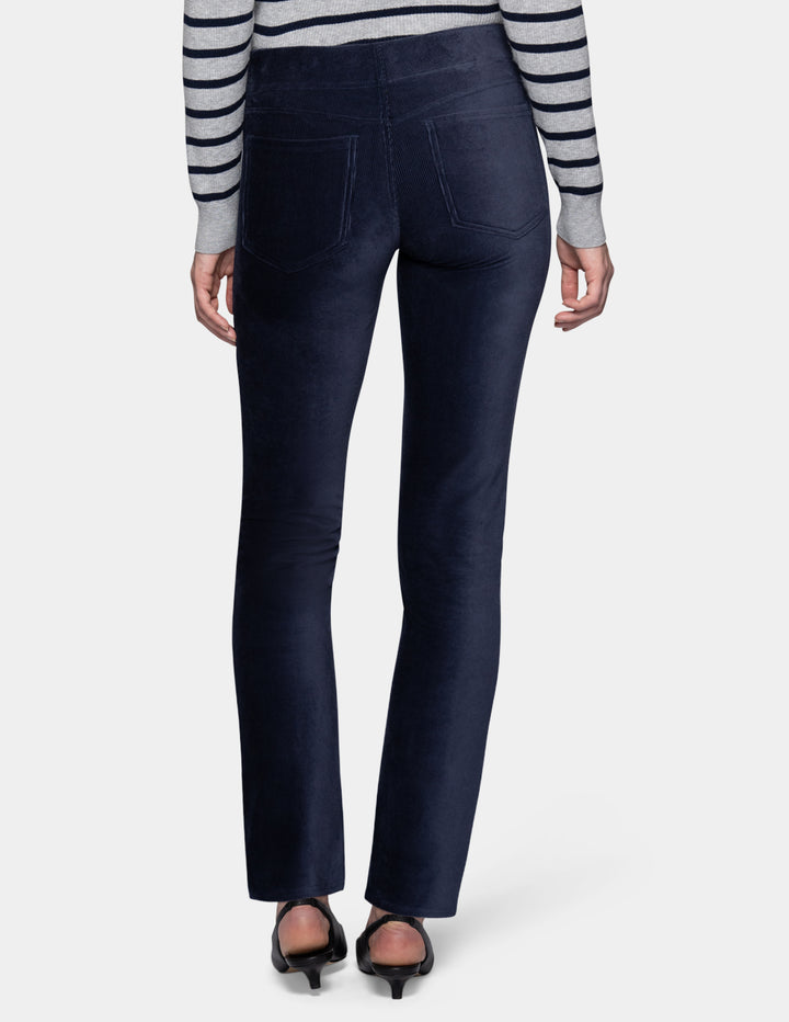 A backside view of a model wearing navy corduroy pants with a long sleeve stripe shirt and pointed toe kitten heels