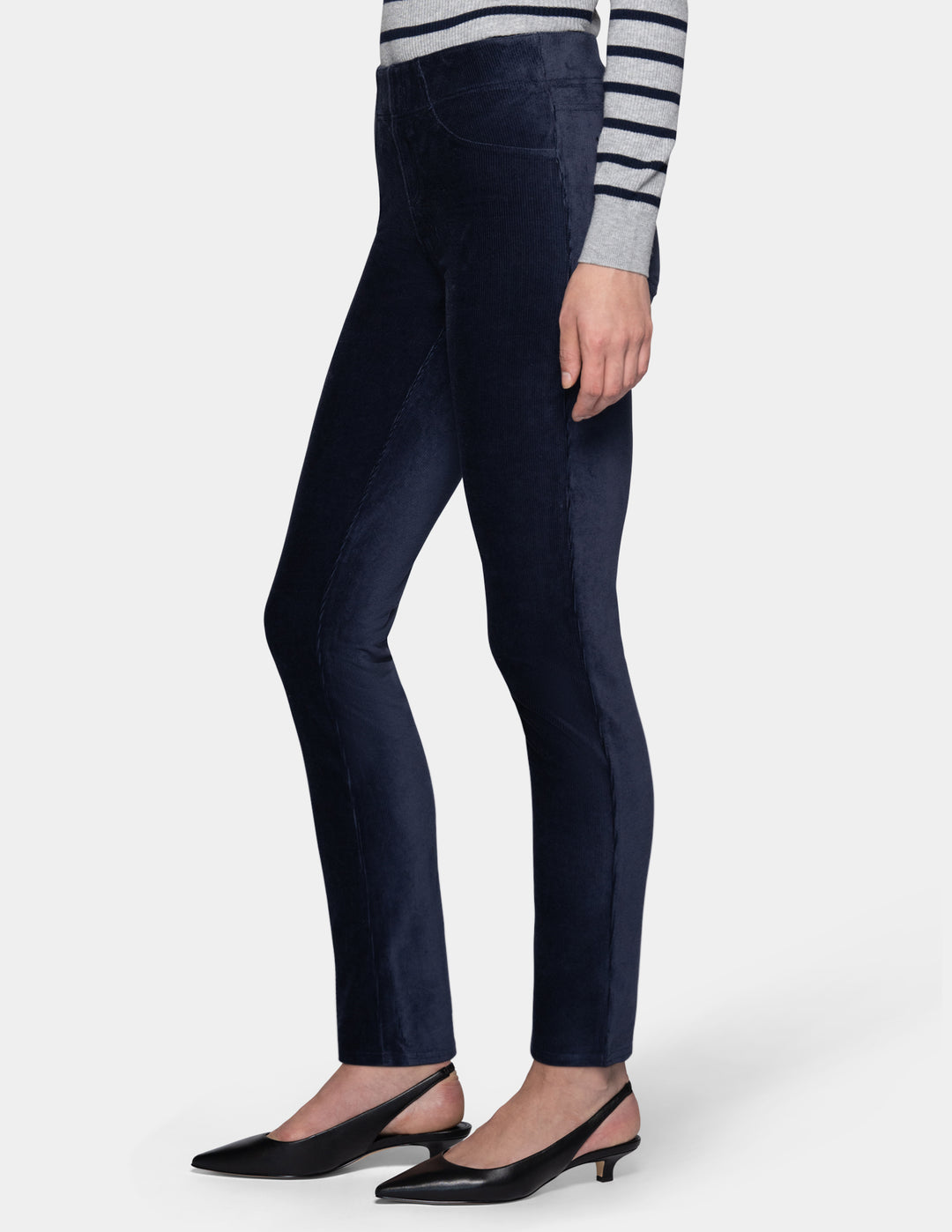 A sideview of a model wearing navy corduroy pants with a long sleeve stripe shirt and pointed toe kitten heels