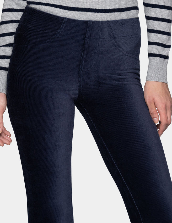 A close-up of a model wearing navy corduroy pants with a long sleeve stripe shirt