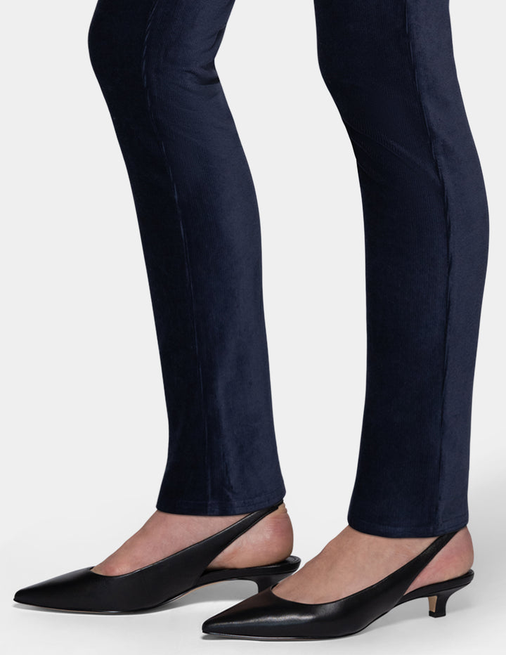 A close-up detailed view of a model wearing navy corduroy pants and black pointed toe kitten heels