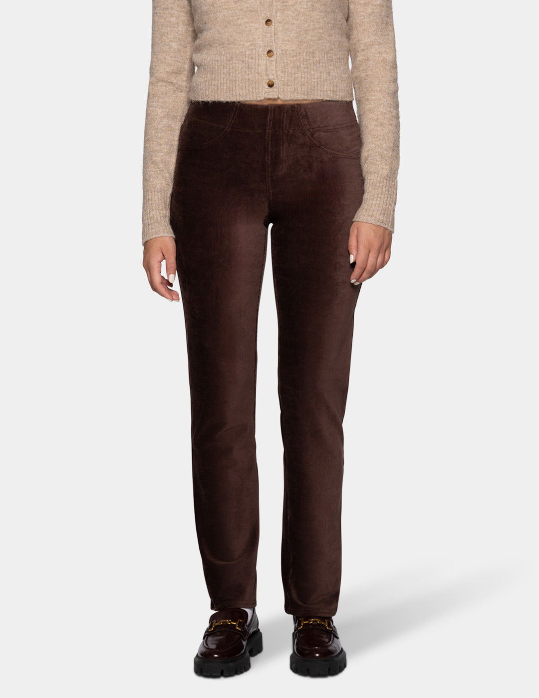 A model wearing brown corduroy pants with a long sleeve beige cardigan and black shoes 