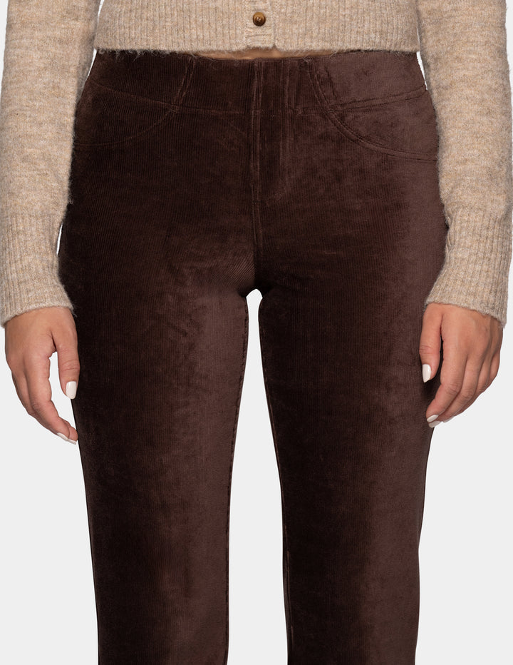 A close-up view of a model wearing brown corduroy pants with a long sleeve beige cardigan