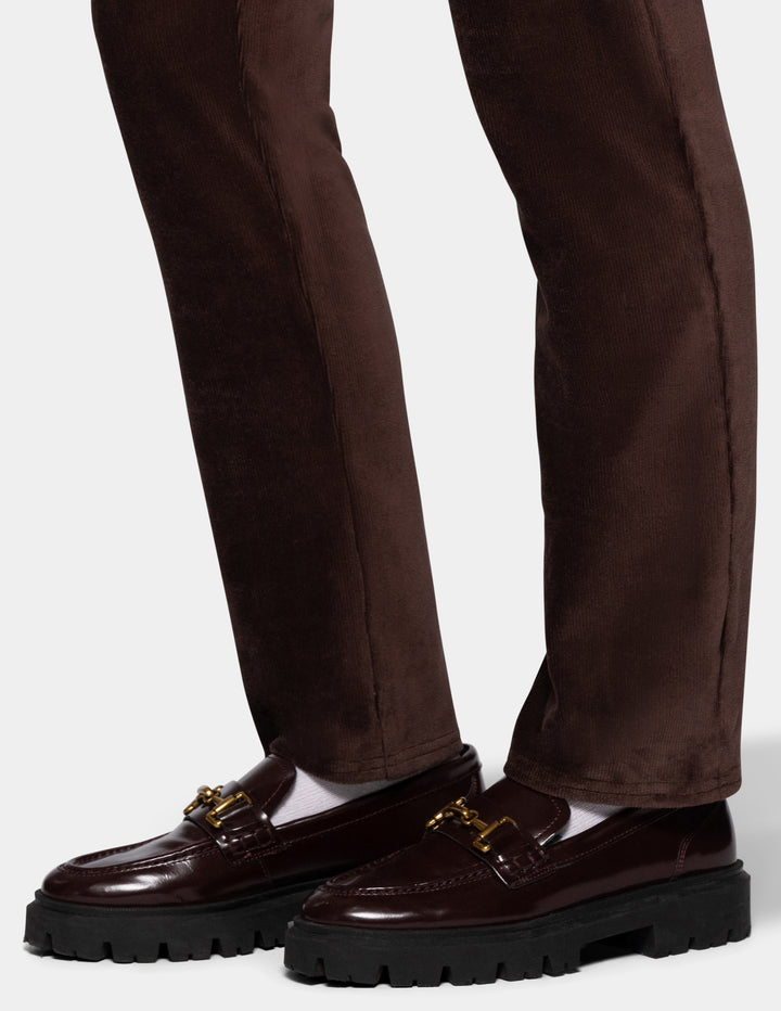 A model wearing brown corduroy pants and black shoes from the knee down