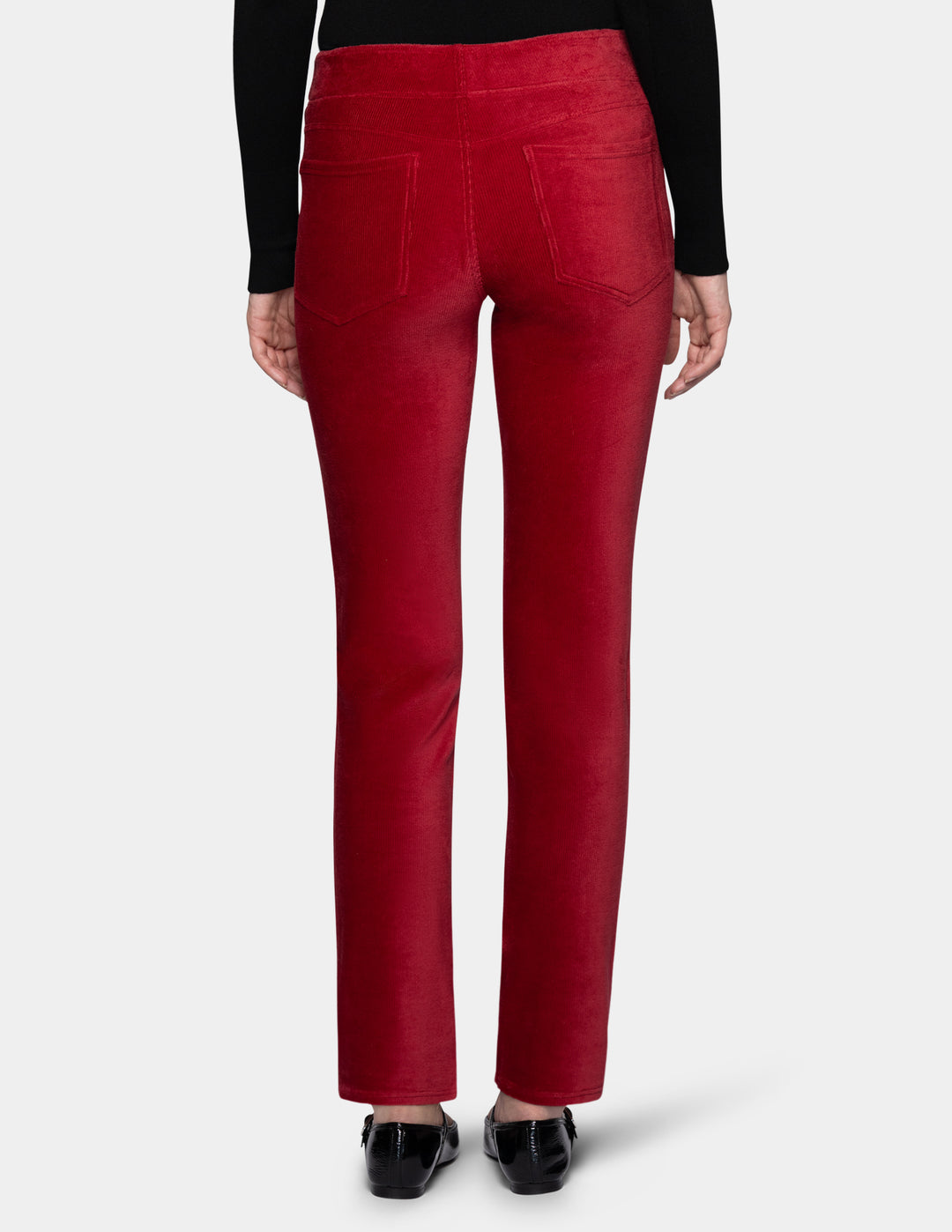 A backside view of a model wearing red corduroy pants with a long sleeve black top and black shoes