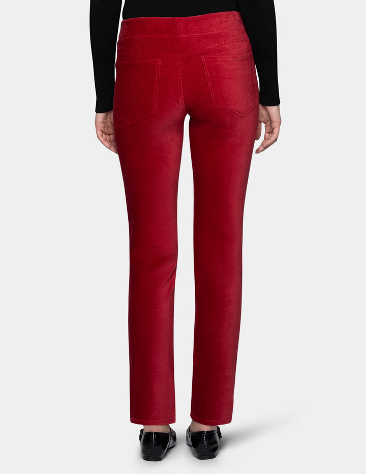 A backside view of a model wearing red corduroy pants with a long sleeve black top and black shoes