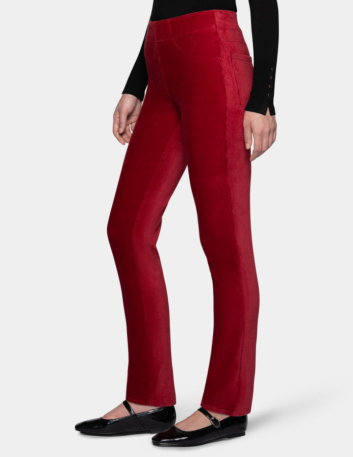 A side view of a model wearing red corduroy pants with a long sleeve black top and black shoes