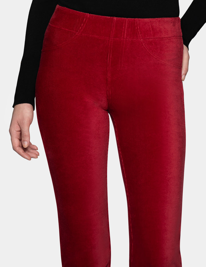 A close-up of a model wearing red corduroy pants with a long sleeve black top