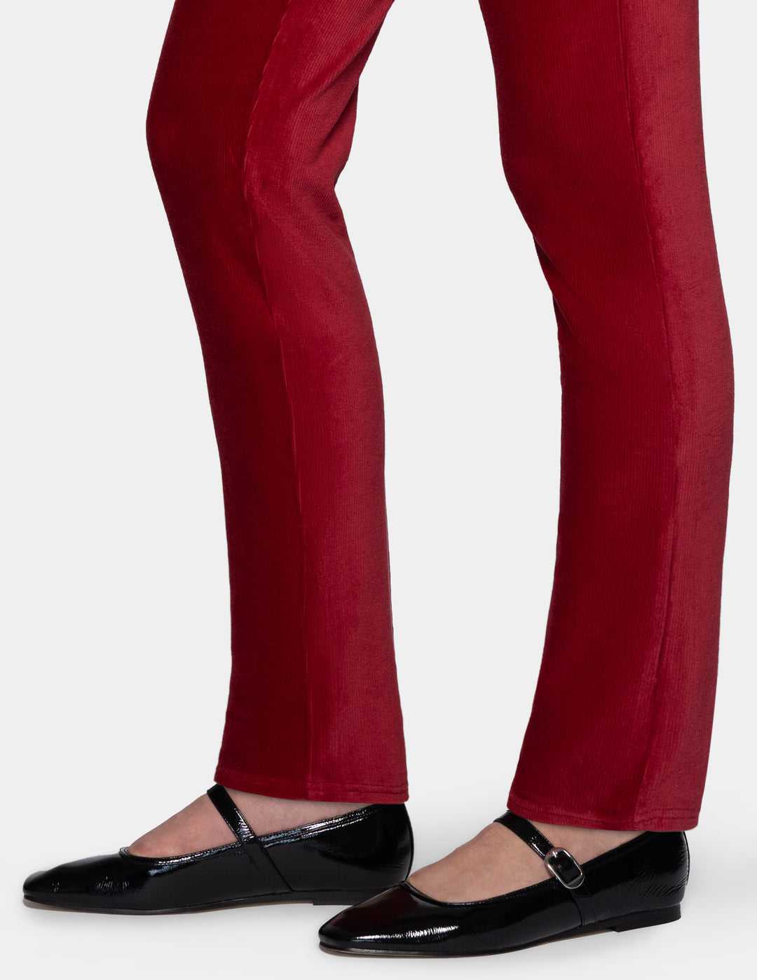 A detailed view of a model wearing red corduroy pants and black shoes from the knee down