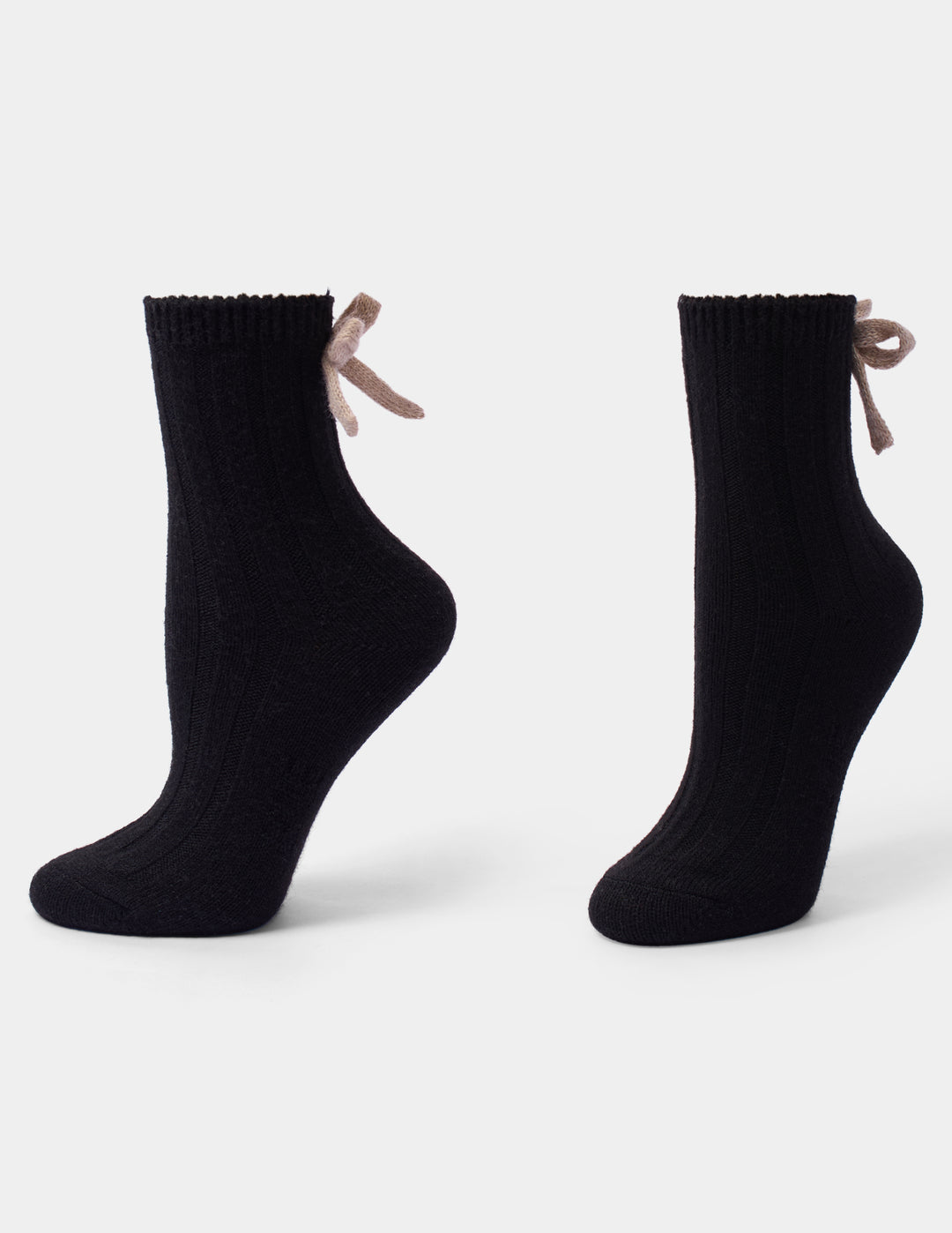 A black anklet sock with a beige bow accent photographed against a light gray background.