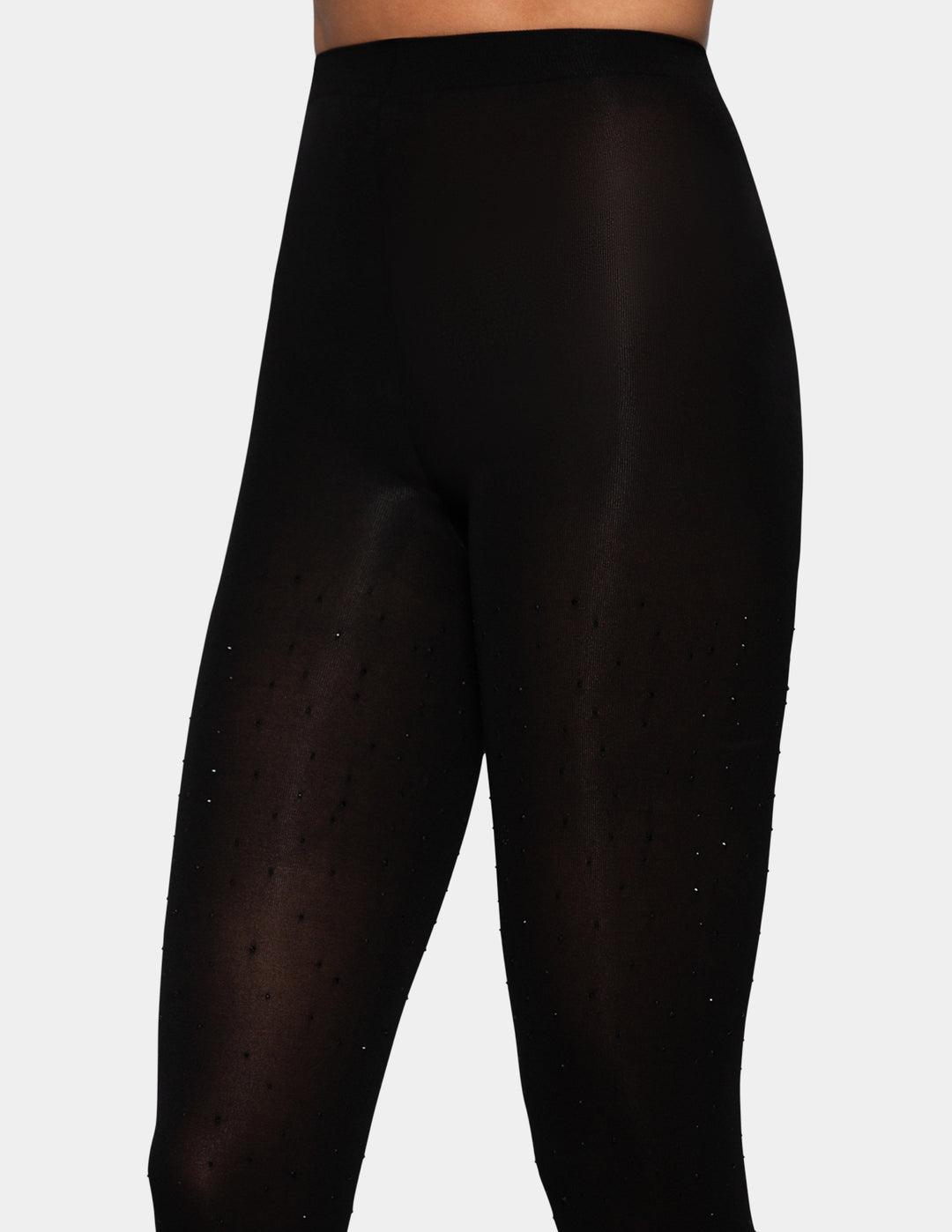 A model wearing black bedazzled opaque tights photographed against a light gray background.