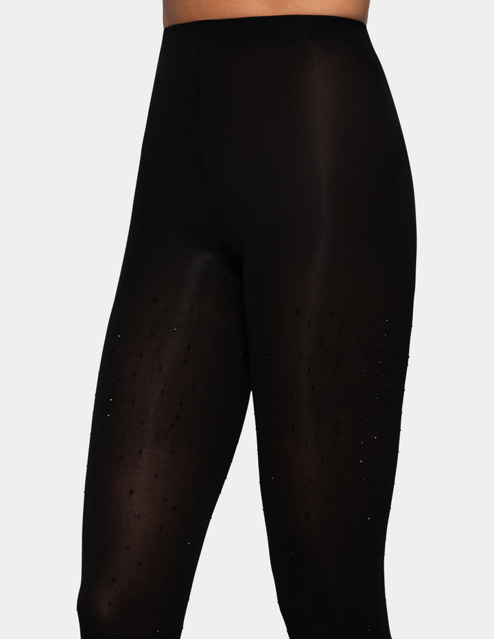 A model wearing black bedazzled opaque tights photographed against a light gray background.