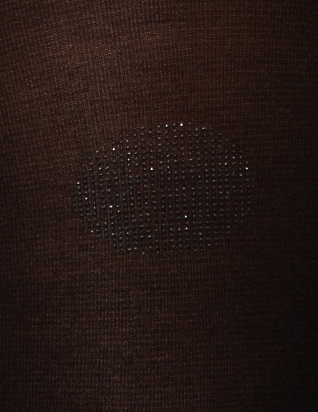 A detailed view of a textured polka dot design displayed on a black fabric material.