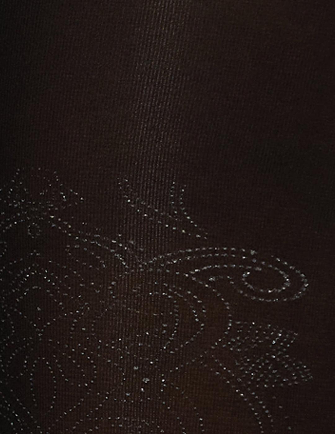 A detailed view of a foil brocade pattern on a black fabric.