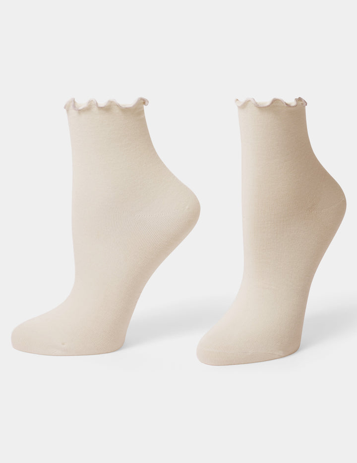 A pair of cream-colored ankle socks with a scalloped edge at the top, displayed on foot forms against a light gray background.