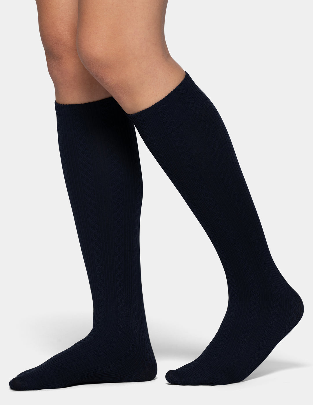 A close-up of a person's legs wearing dark navy blue knee-high socks against a light gray background.