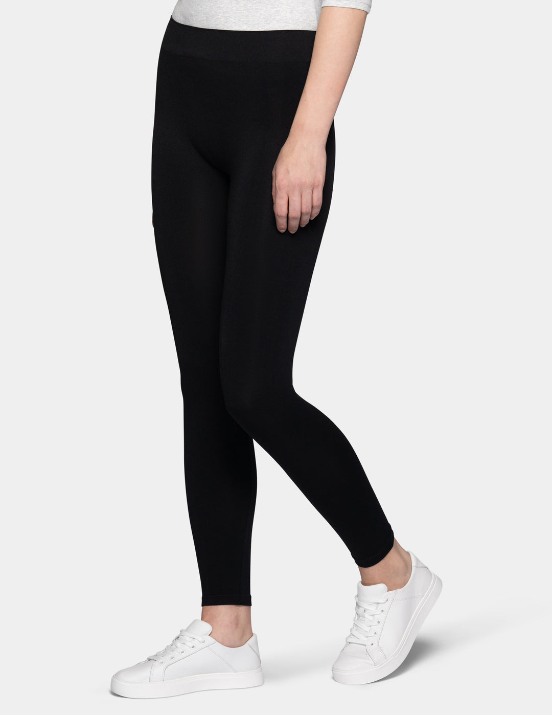 A sideview of a model wearing black leggings, light grey 3/4 sleeve shirt, and white sneakers.