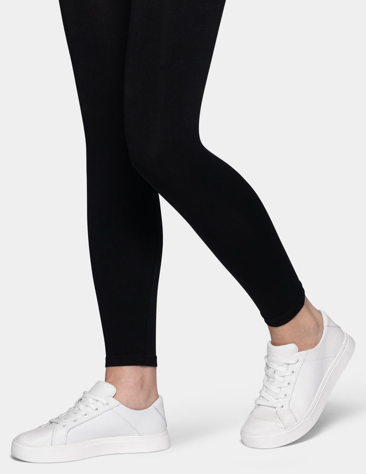 A model wearing black leggings and white sneakers.