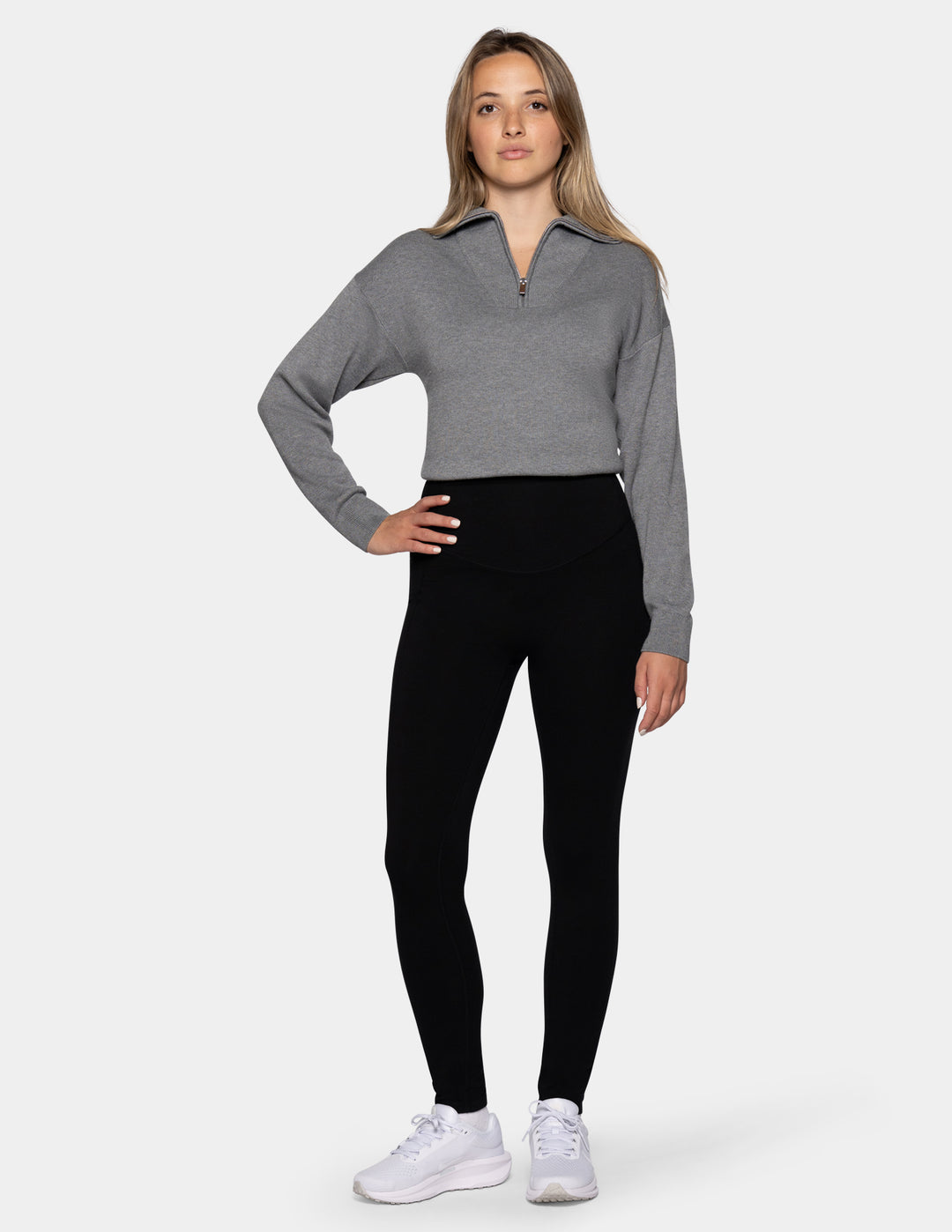 A model wearing black leggings and a gray zip-up sweatshirt.