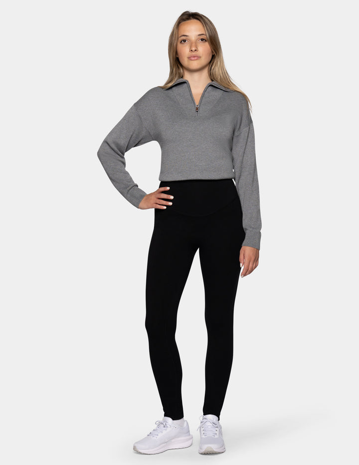 A model wearing black leggings and a gray zip-up sweatshirt.