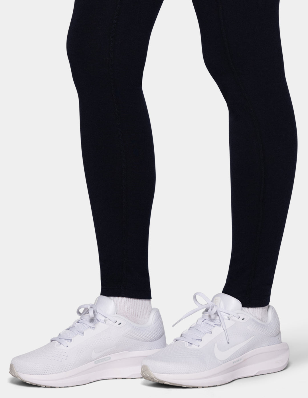A model wearing navy leggings and white sneakers.