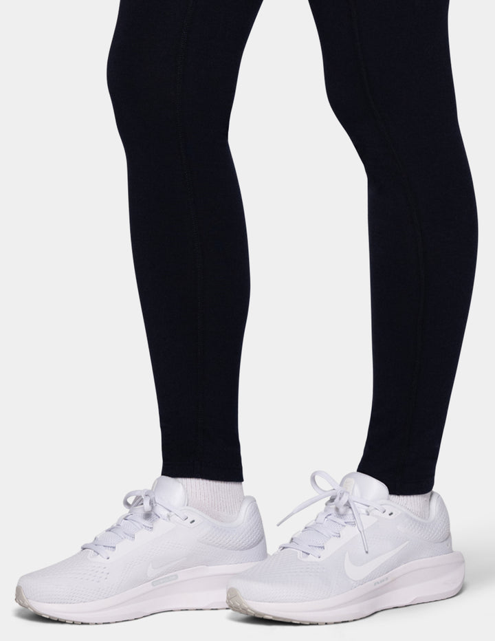 A model wearing navy leggings and white sneakers.