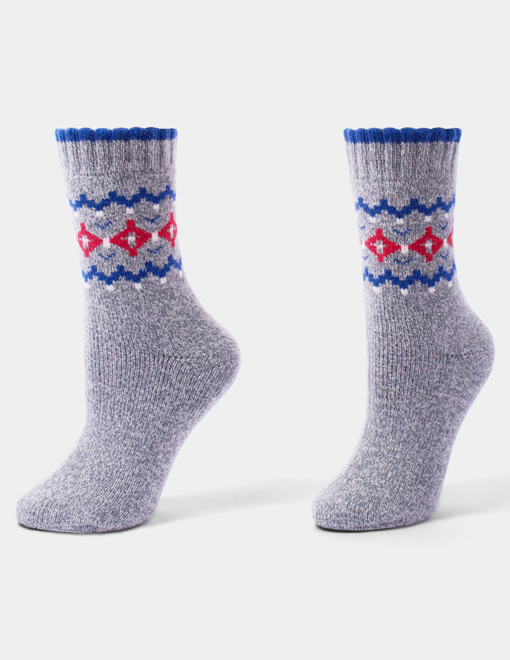 A pair of grey, blue, and red holiday pattern crew socks with little white accents displayed against a light grey background.