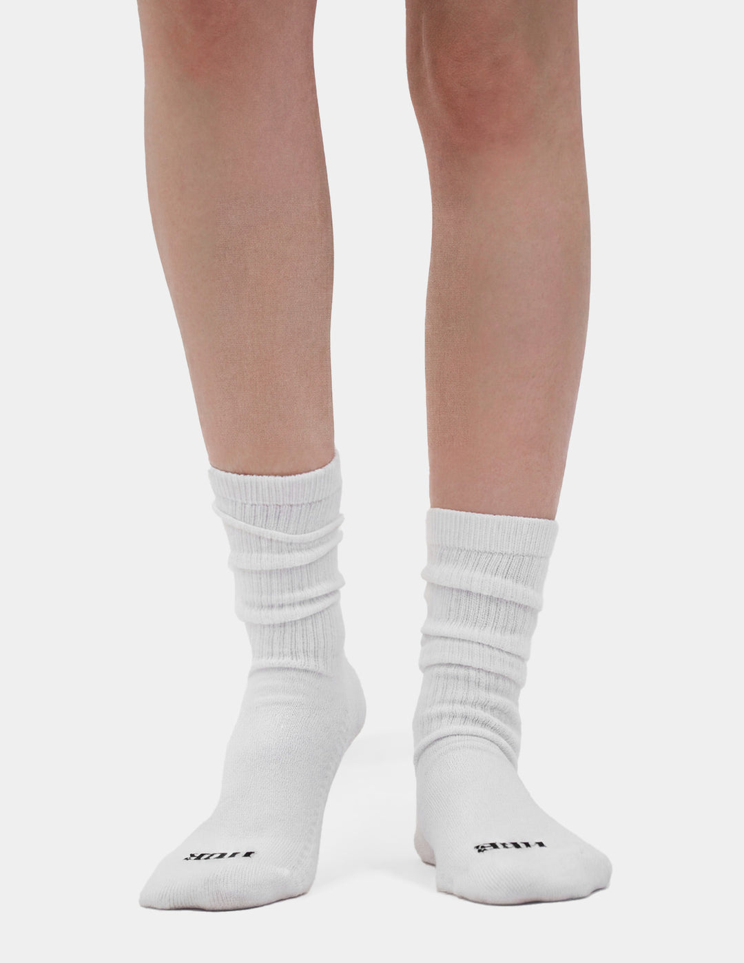 White socks with HUE brand logo worn by a person on a light gray background