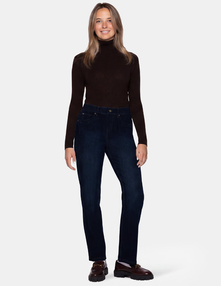 A model wearing dark blue denim pants, a long sleeve brown top, and brown loafers photographed against a light gray background.